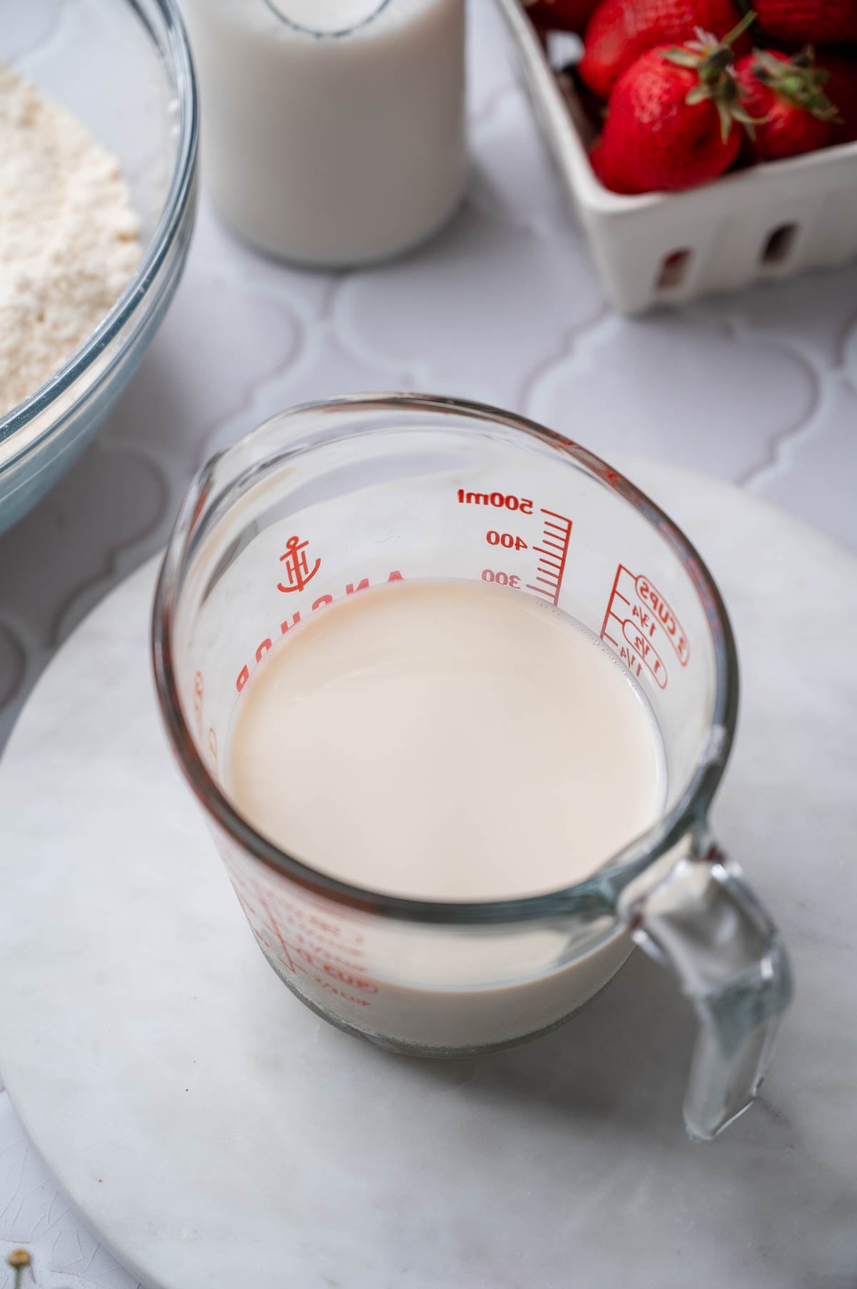 a glass measuring cup filled with soy milk and vinegar