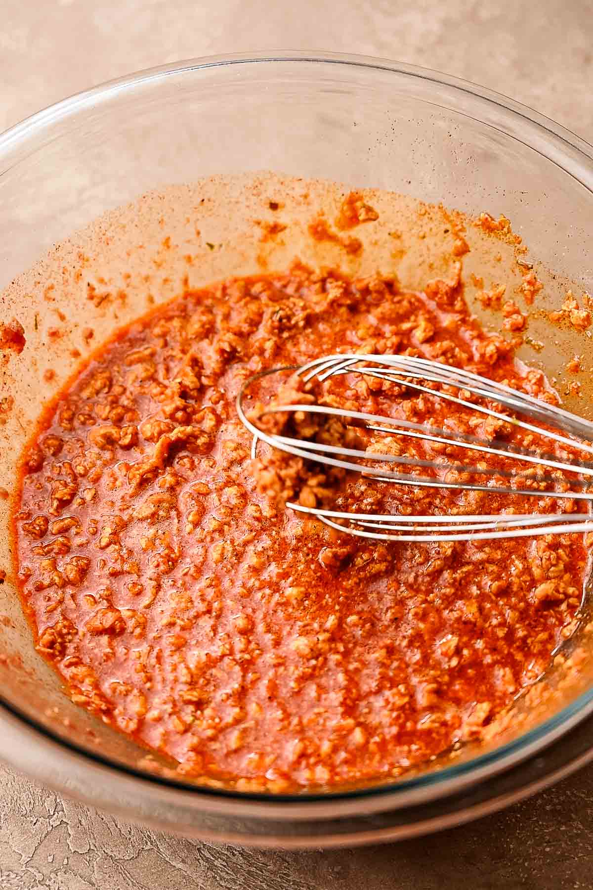 a metal whisk combining TVP with the spiced broth.