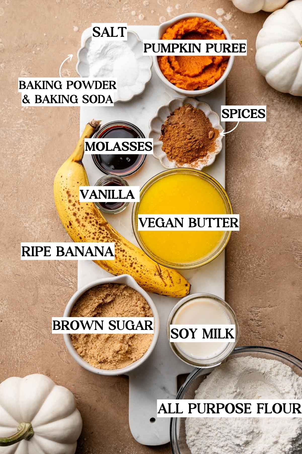 ingredients like banana, pumpkin puree, melted vegan butter, sugar, baking soda and powder on a marble tray.