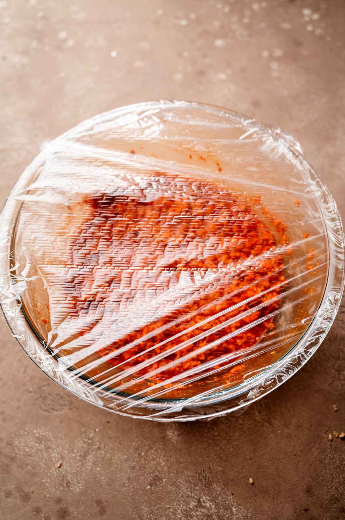 the glass bowl of vegan chorizo covered in plastic.