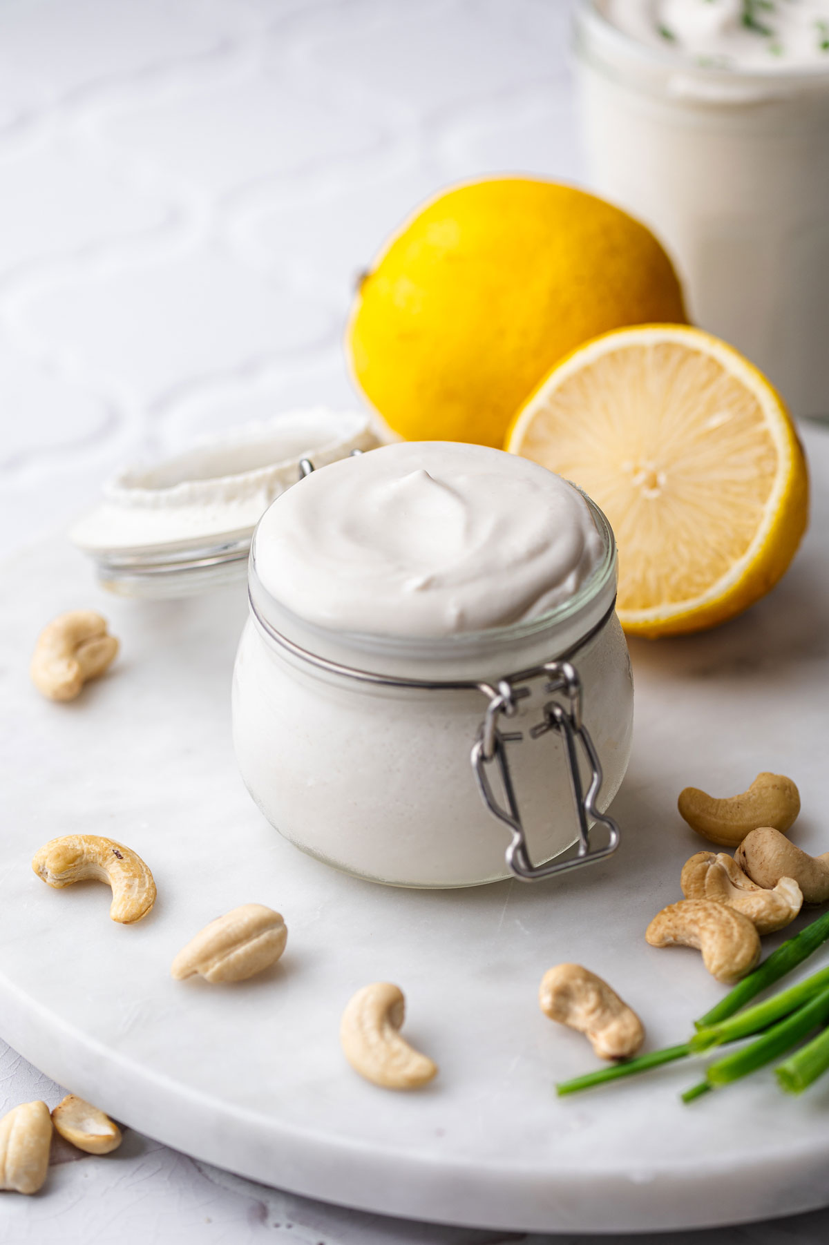 a small jar of vegan cashew sour cream with lemon in the background.
