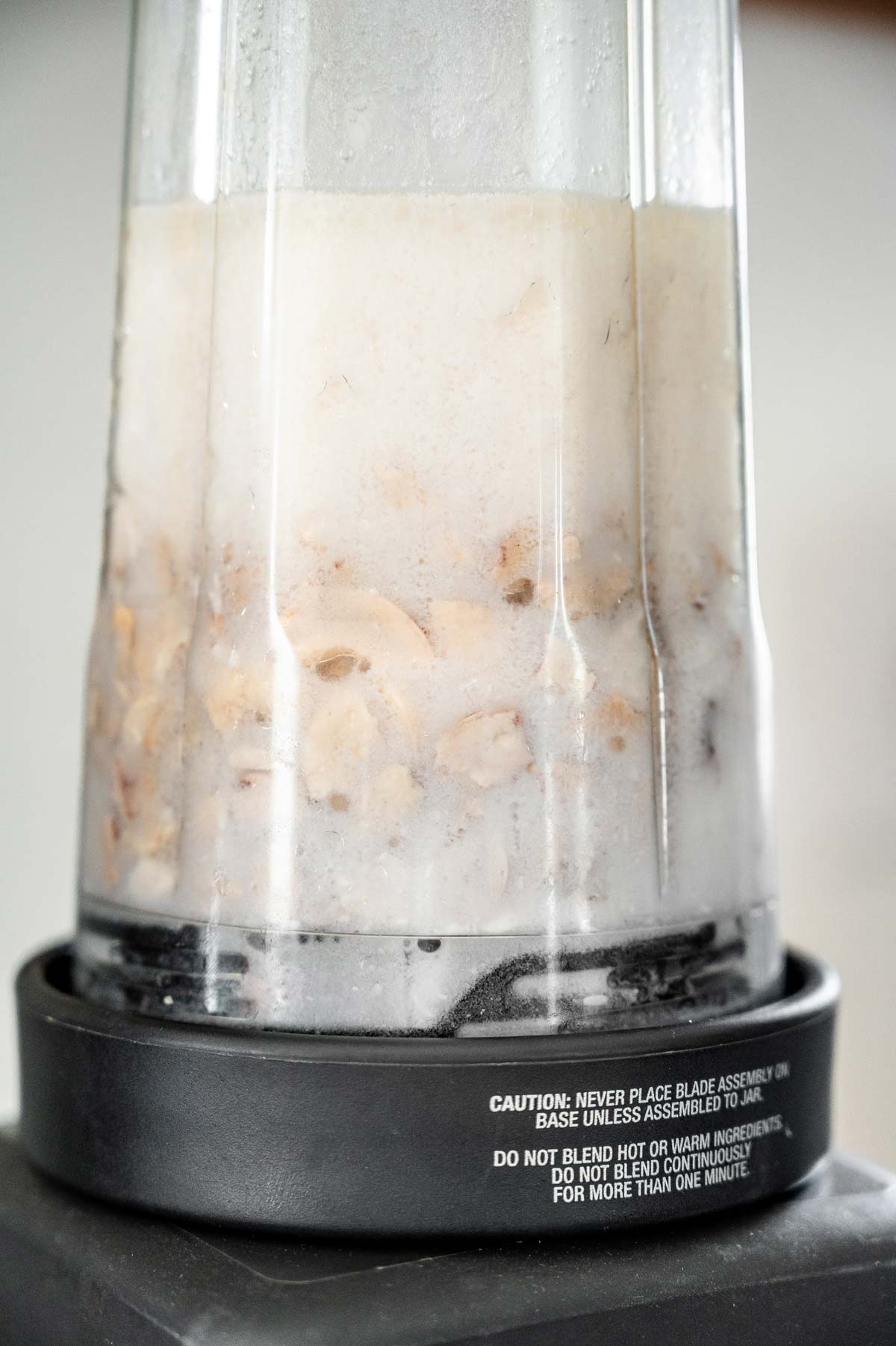 a blender jar filled with dairy free cashew sour cream ingredients on a blender base.