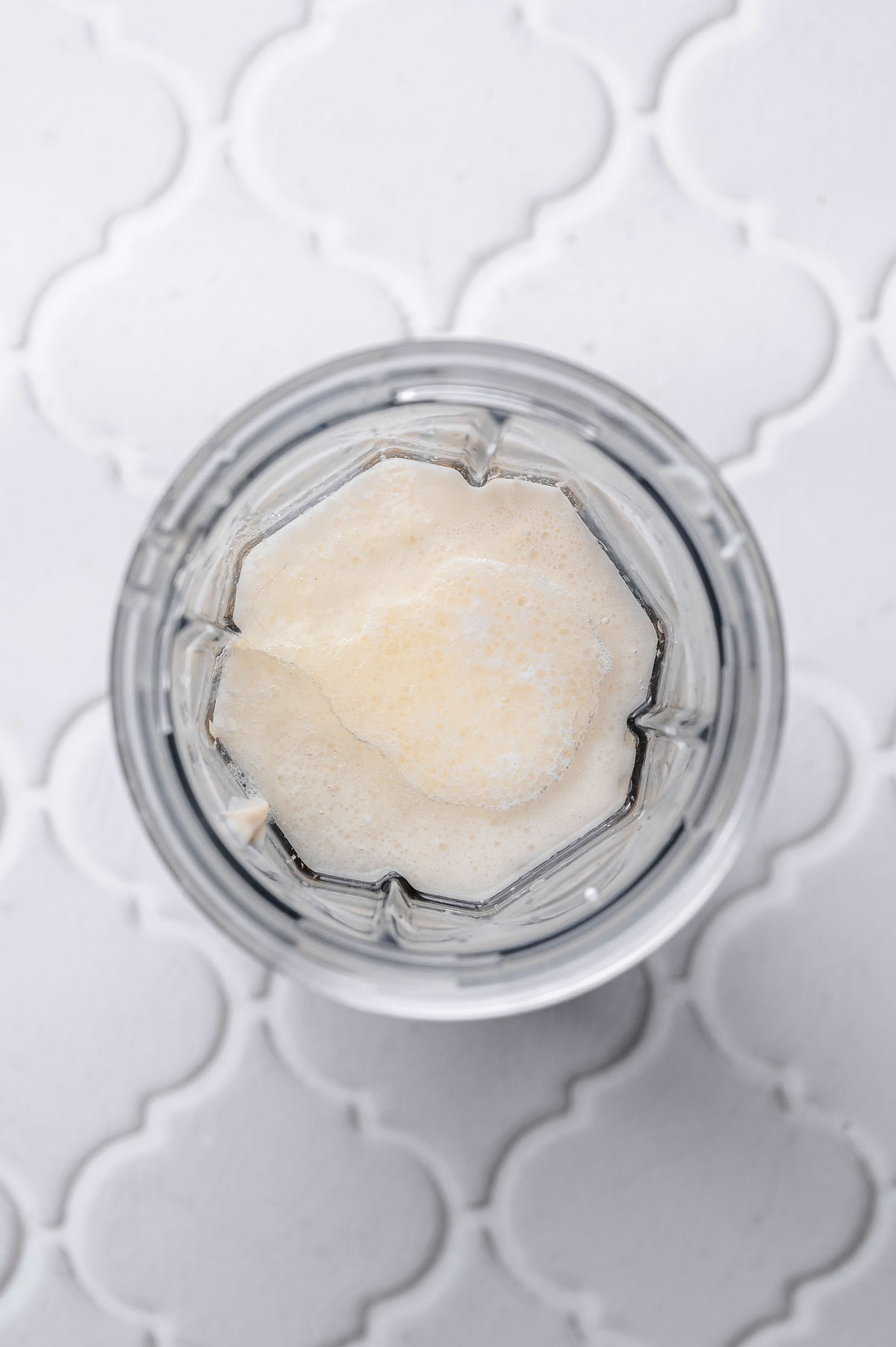 a small blender jar with cashews, coconut cream, and oil added.