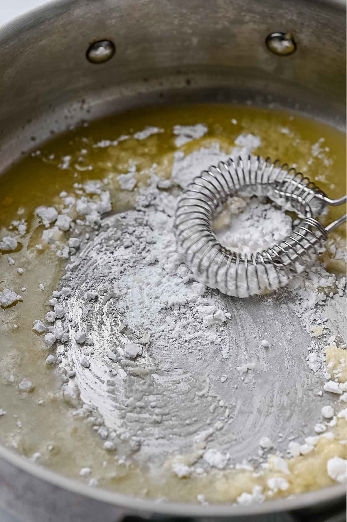 Whisking tapioca starch into melted vegan butter in a saucepan.
