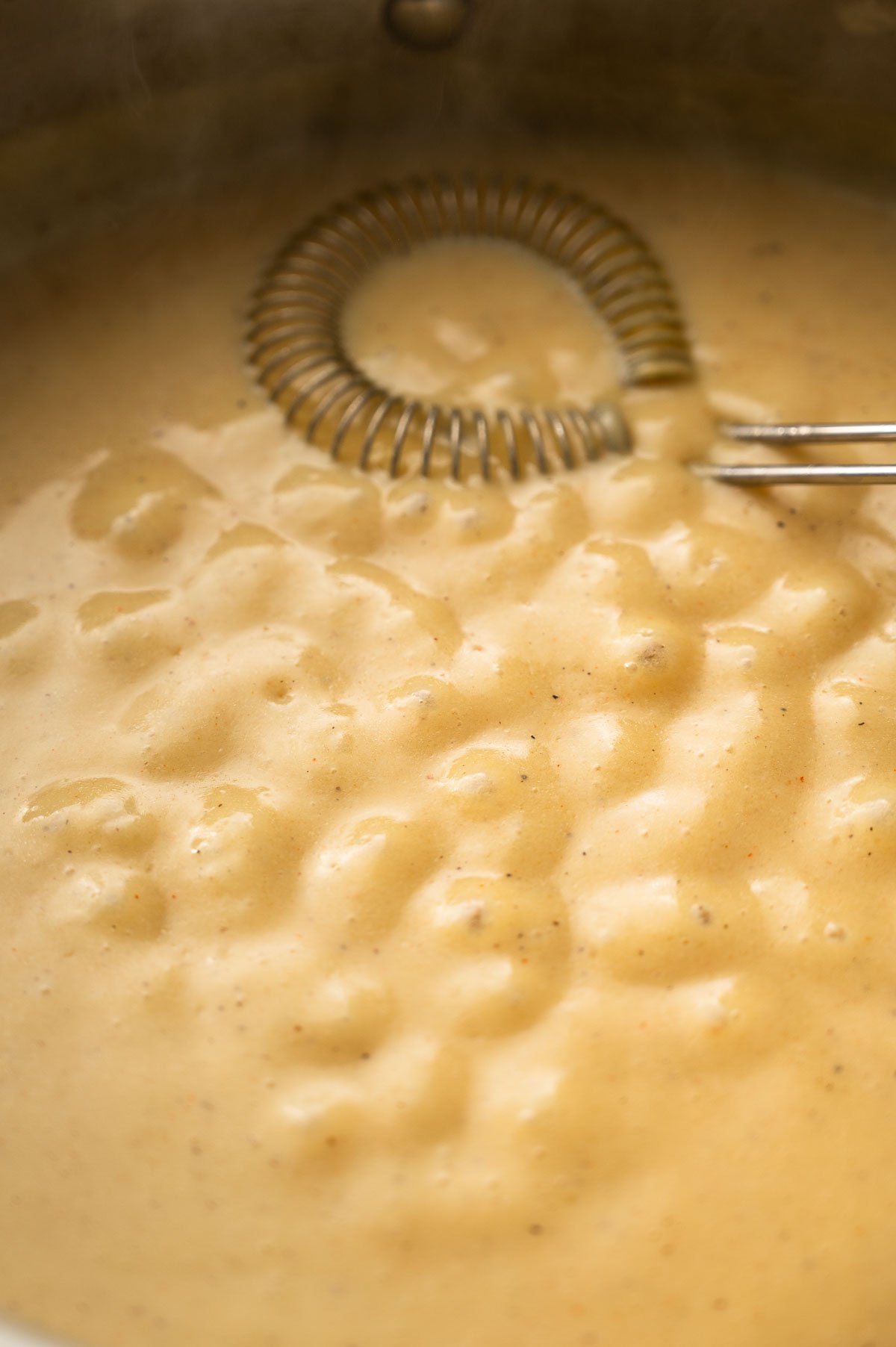 Thickening vegan cheese sauce bubbling in the pan.