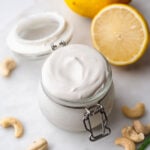 a small jar of vegan cashew sour cream with lemon in the background.