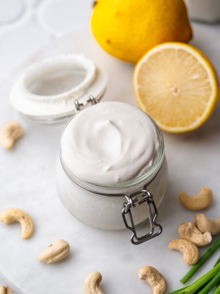a small jar of vegan cashew sour cream with lemon in the background.