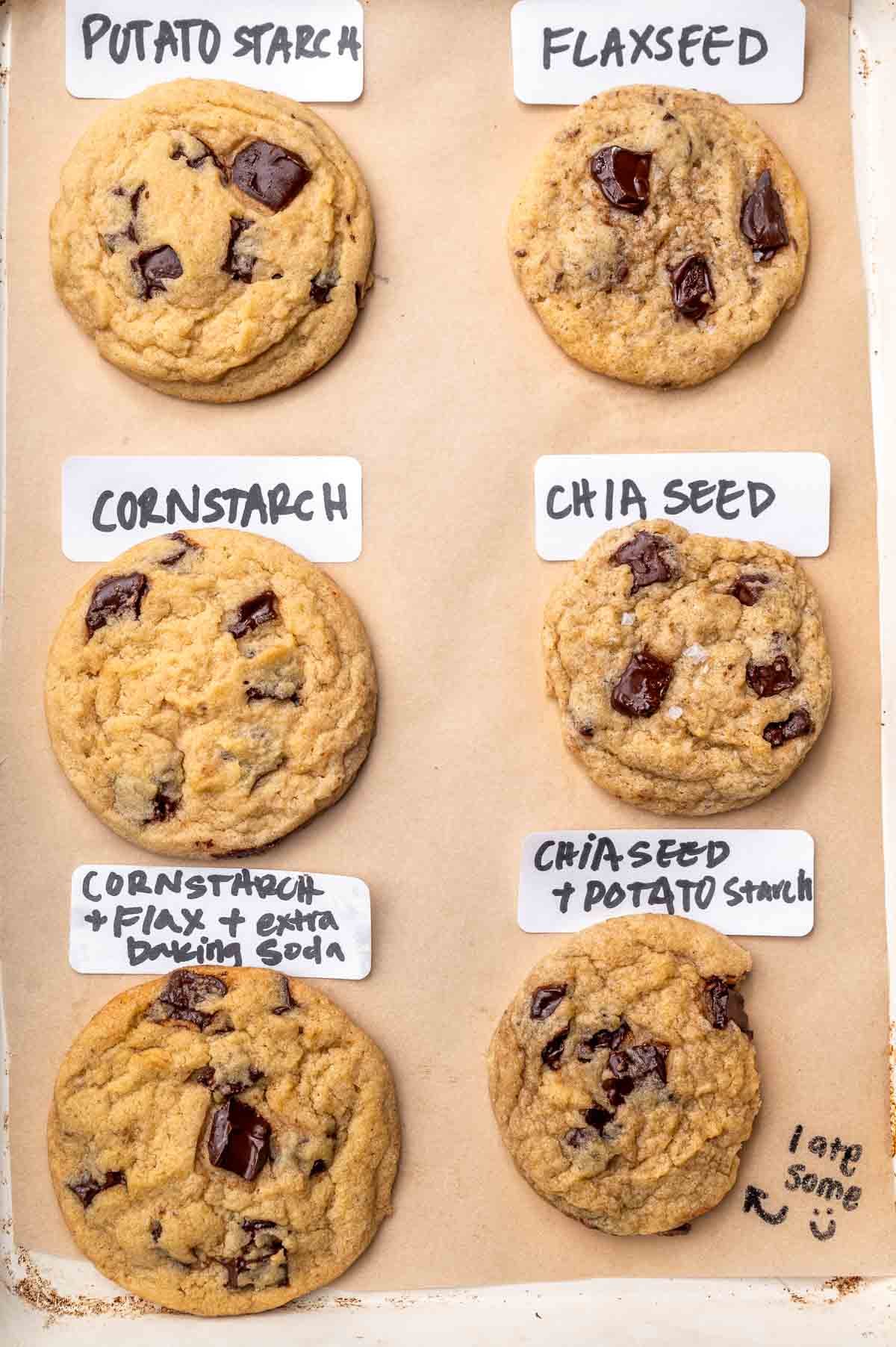 6 vegan chocolate chip cookies on a baking sheet with labels for different egg replacers used.