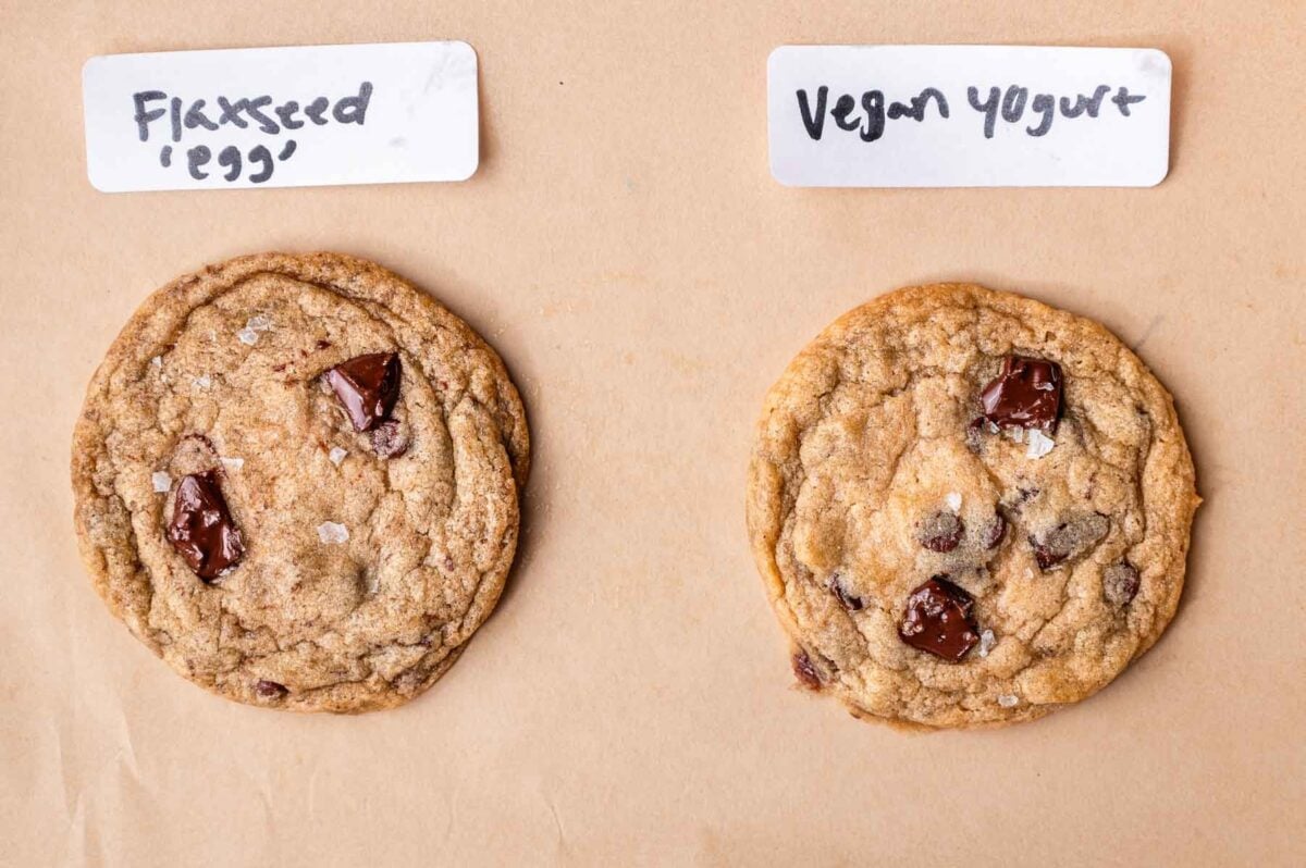 two cookies baked with different vegan egg substitutes on parchment.