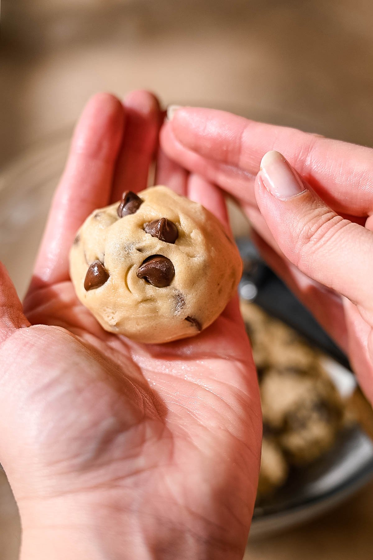 two hands rolling the vegan chocolate chip cookie dough into a ball.