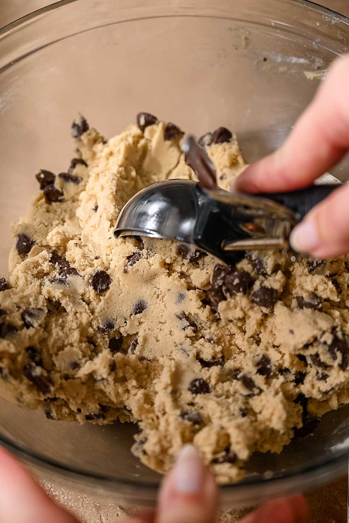 Thick vegan chocolate chip cookie dough in a glass bowl, ready to scoop.