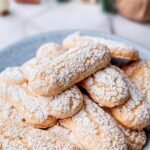 close-up of vegan ladyfinger cookies with cracked tops and a powdered sugar coating.