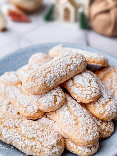 close-up of vegan ladyfinger cookies with cracked tops and a powdered sugar coating.