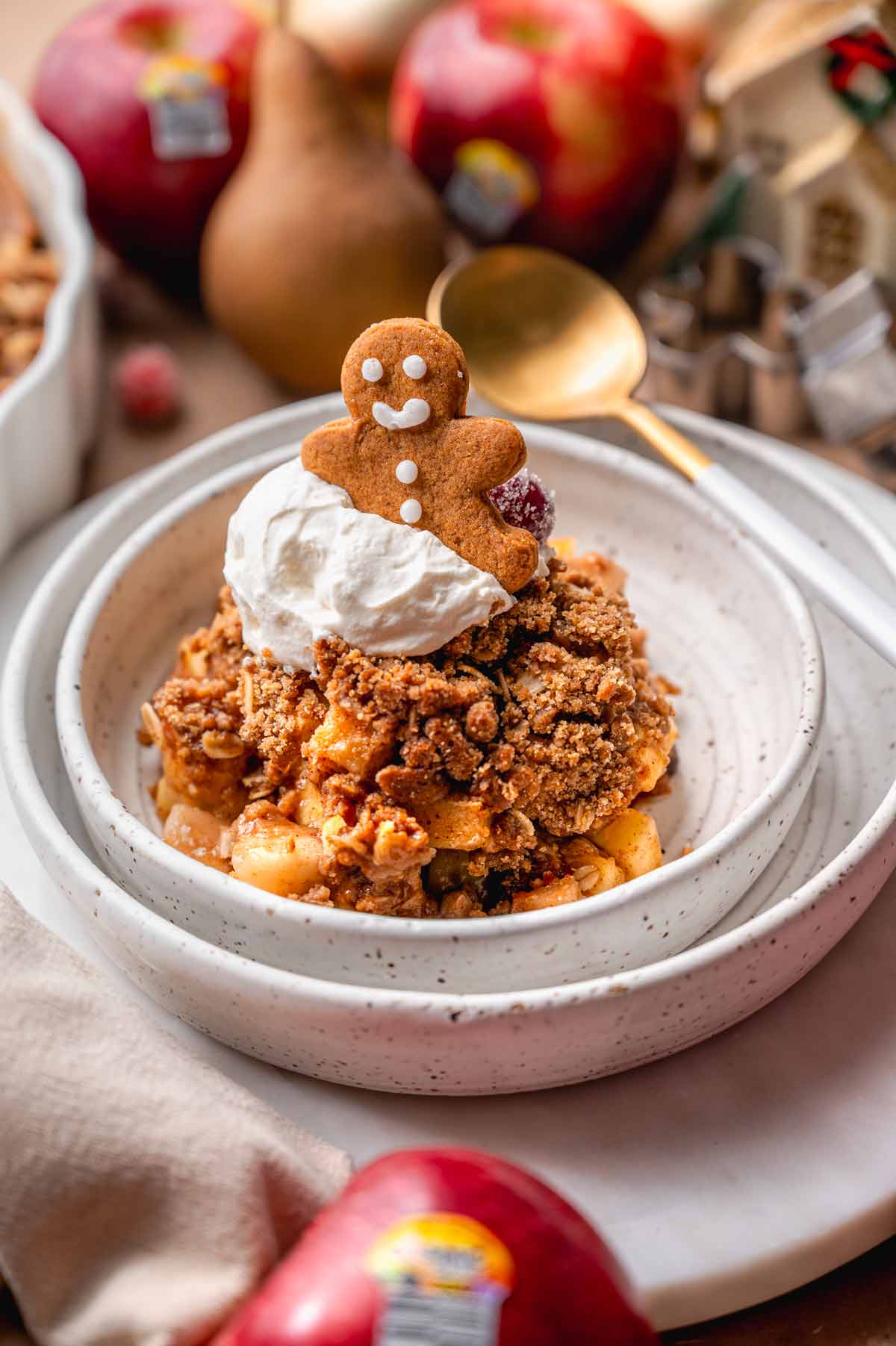 a white speckled ceramic dish with apple crisp topped with ginger crumble.
