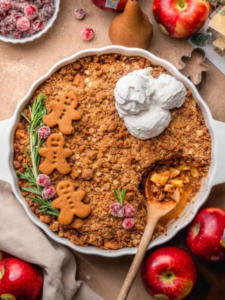 a white baking dish with a vegan apple crisp topped with gingerbread crumble.