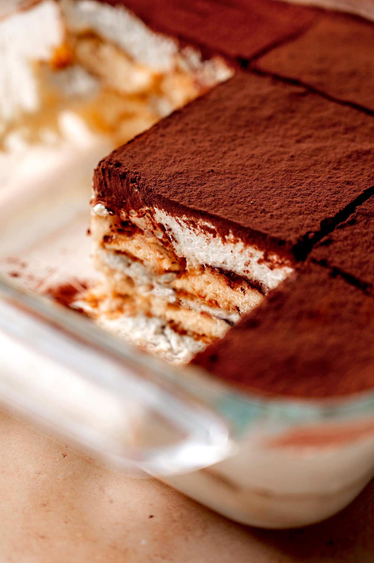 a slice of homemade vegan tiramisu in a glass pan.