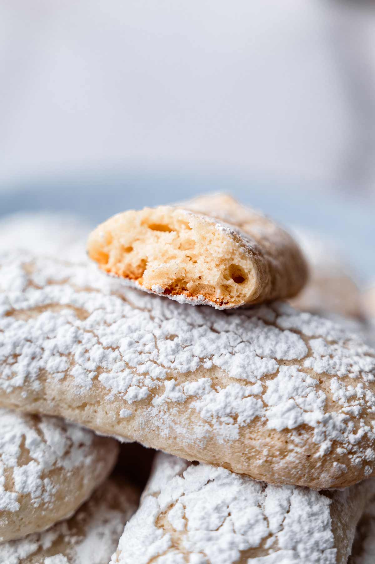 Close-up of a broken vegan ladyfinger cookie showing a light, airy sponge texture inside.