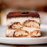 a slice of vegan tiramisu on a ceramic plate.