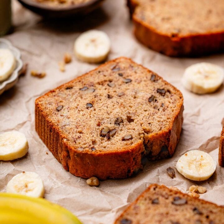 a slice of vegan banana bread with walnuts on a crumpled brown parchment.