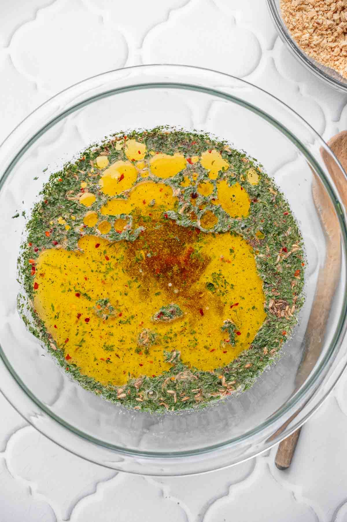 Veggie broth mixed with olive oil, spices, and seasonings in a bowl to hydrate textured vegetable protein.