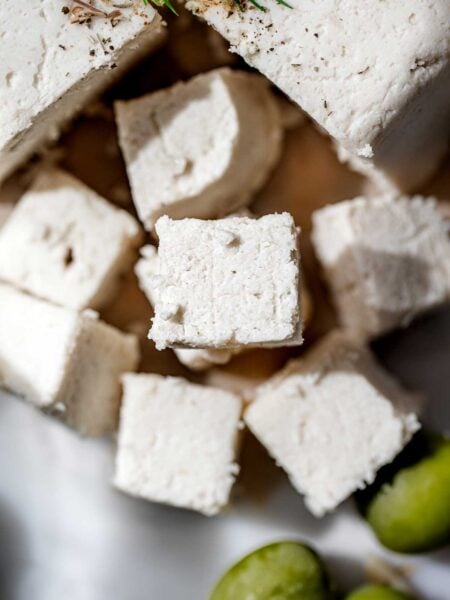 Close-up of homemade vegan feta cheese cut into rustic cubes, showing a crumbly texture and clean edges.