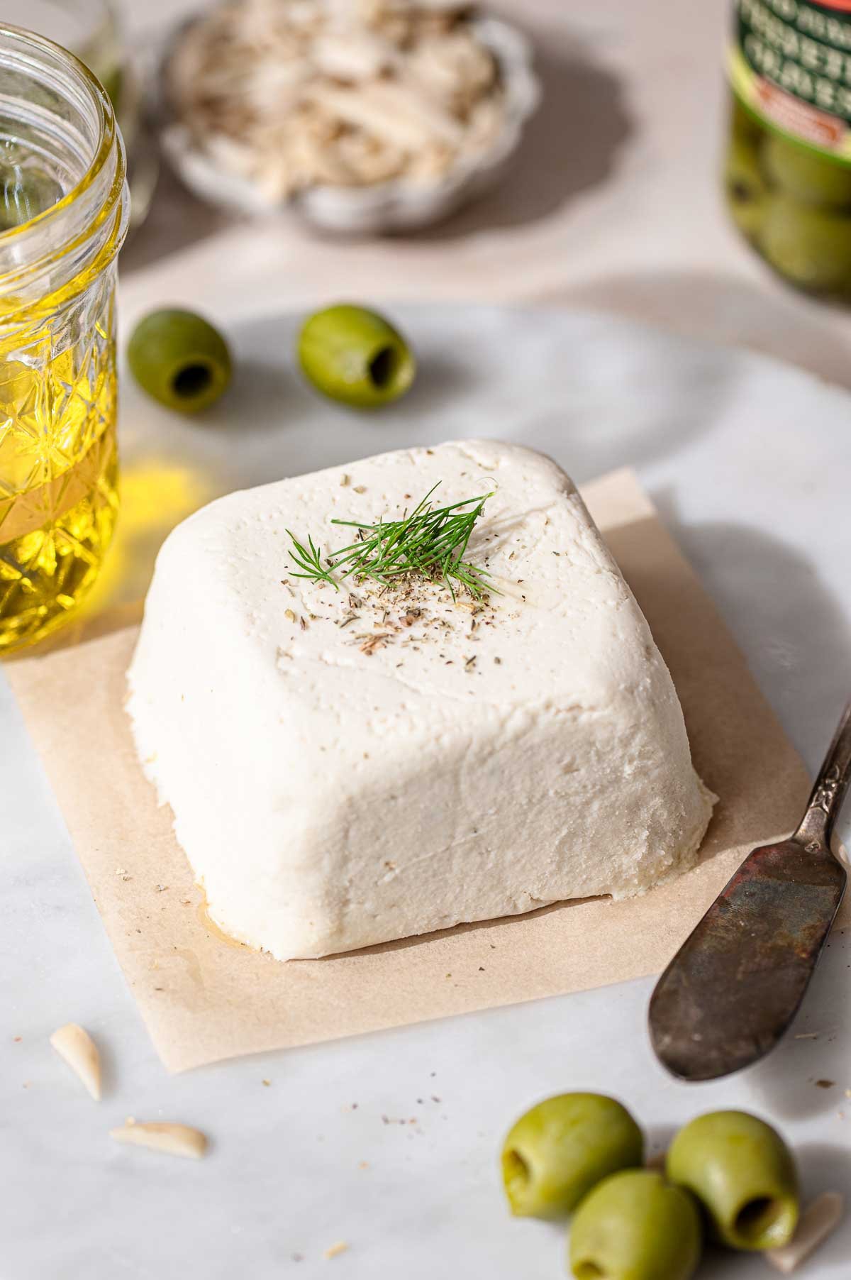 a block of vegan feta on brown parchment paper before slicing.