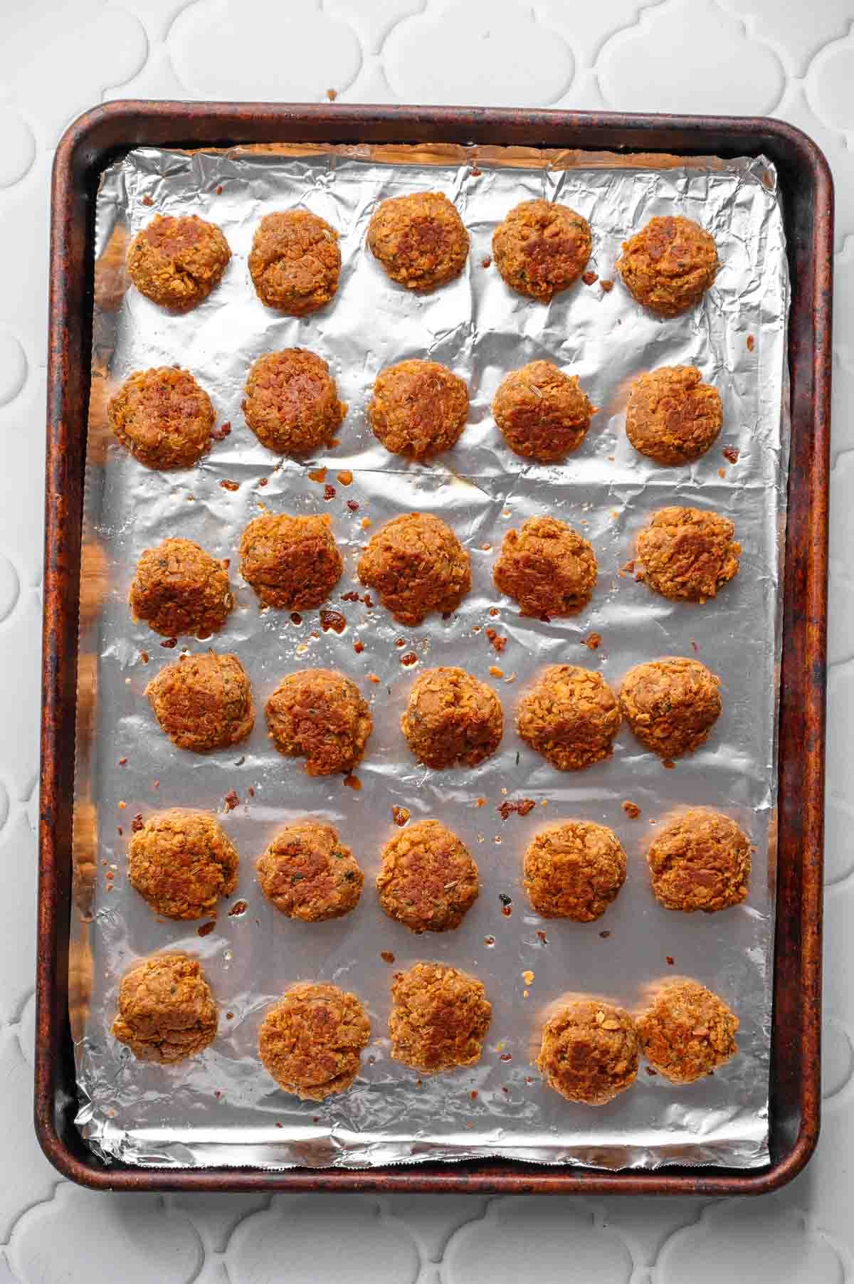 baked vegetarian meatballs on a foil lined baking pan.