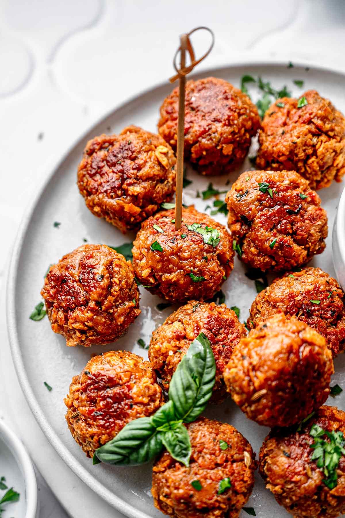 Baked vegan meatballs arranged on a platter as an appetizer, garnished with herbs and served without sauce.