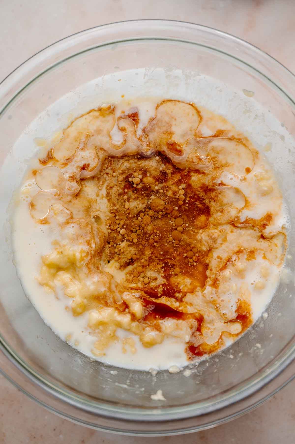 wet ingredients like soy milk and oil with mashed bananas in a large bowl.