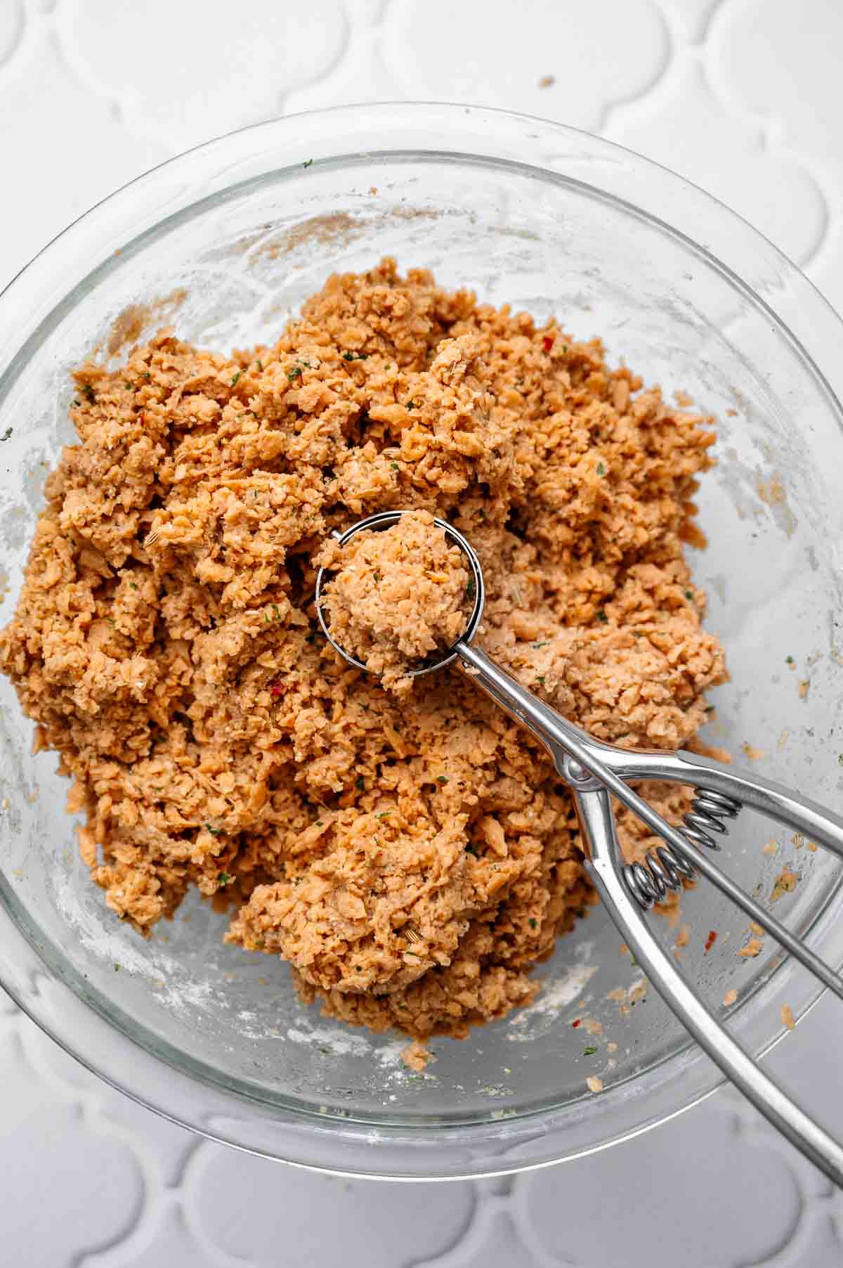 Scooping vegan meatball mixture with a cookie scoop to portion evenly sized meatballs.