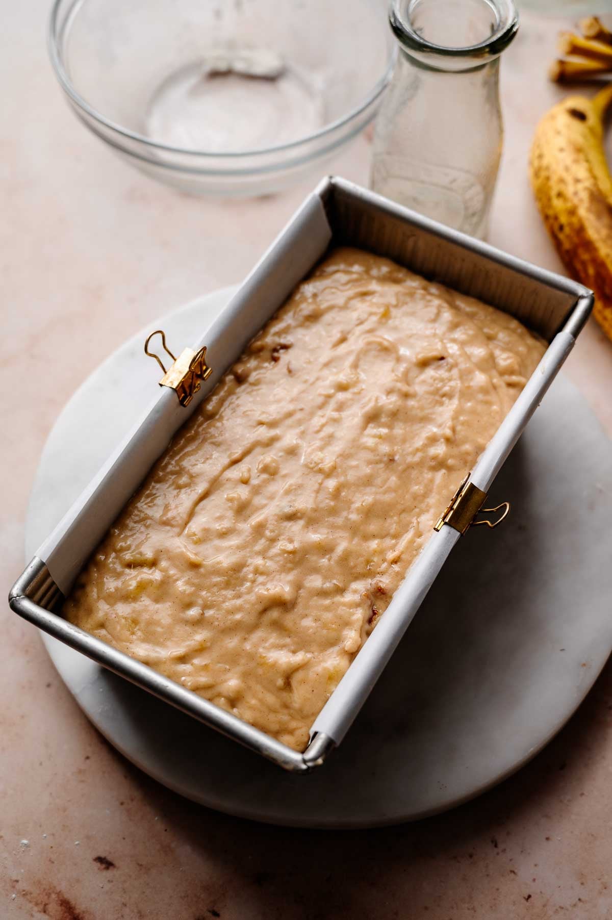 the vegan banana bread batter in a parchment lined metal loaf pan.