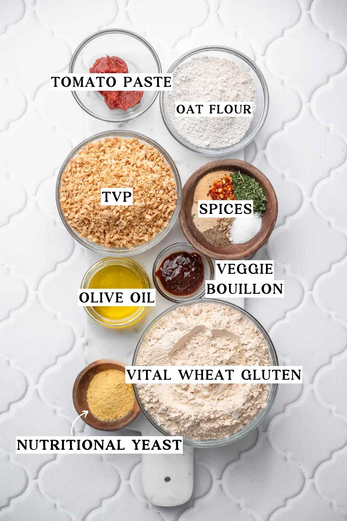 Ingredients for vegan meatballs arranged in bowls, including textured vegetable protein, vital wheat gluten, oat flour, tomato paste, olive oil, nutritional yeast, spices, and veggie bouillon.