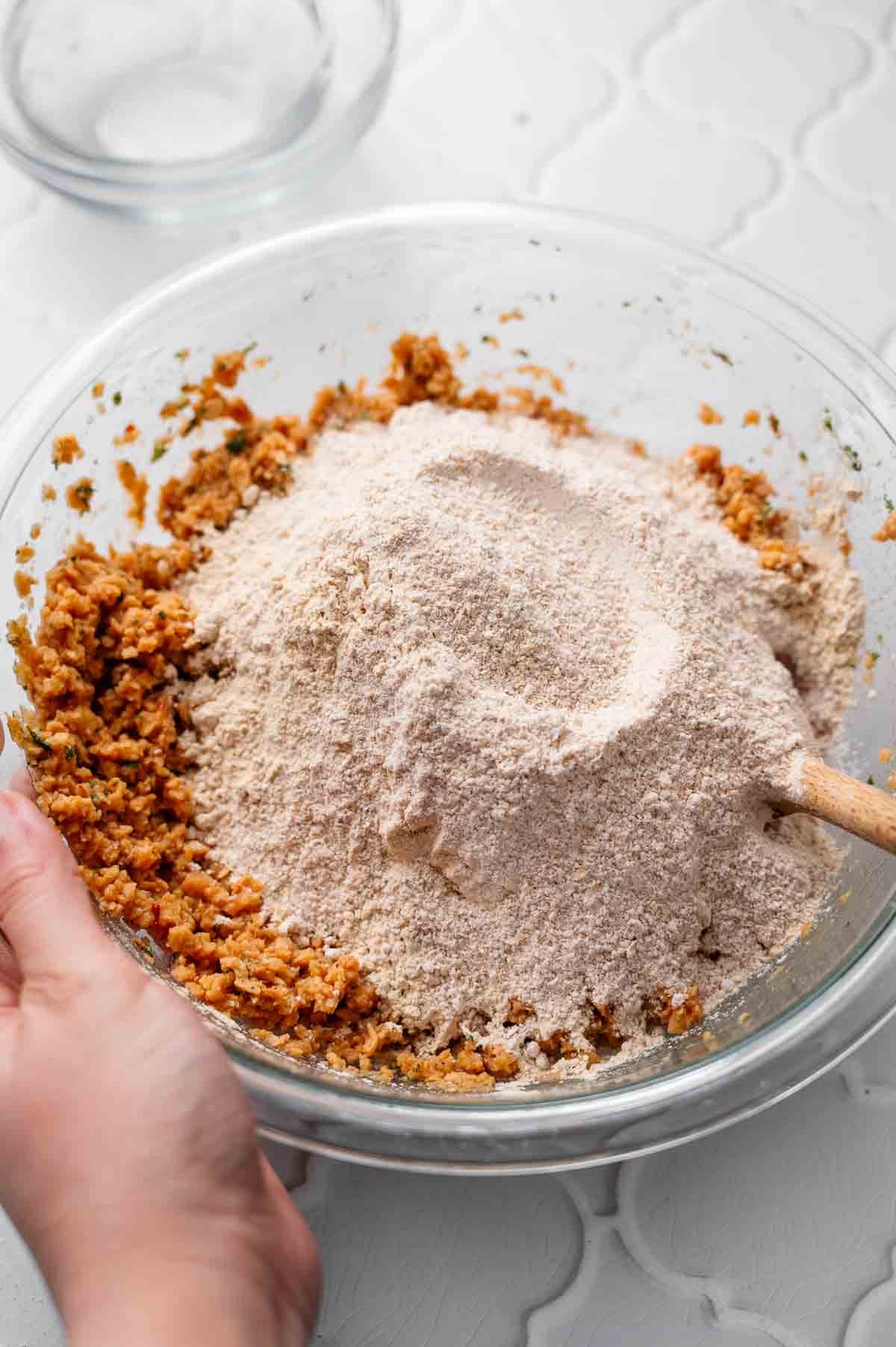Vital wheat gluten being added to a bowl of hydrated textured vegetable protein during tvp meatball preparation.