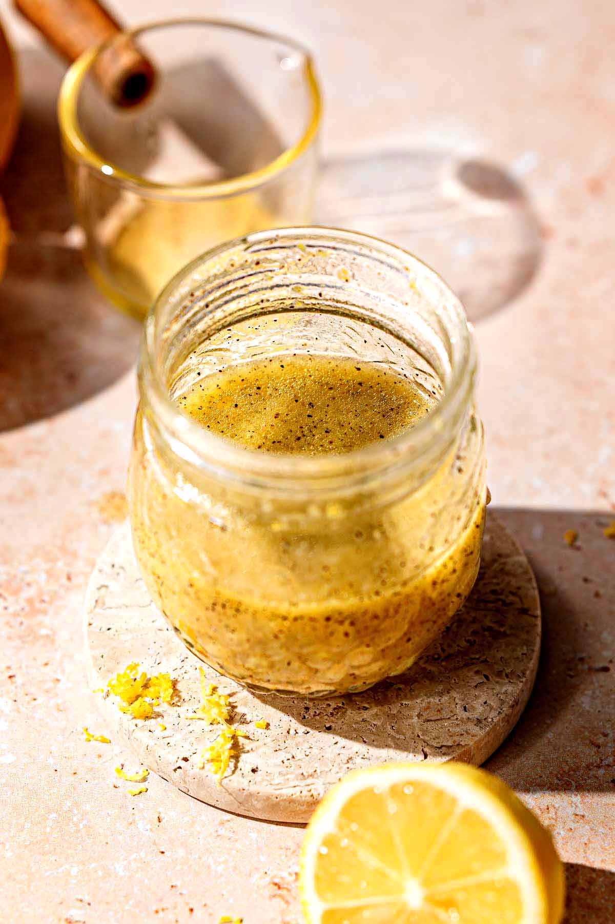 a small glass jar filled halfway with a homemade lemon dressing for salads.