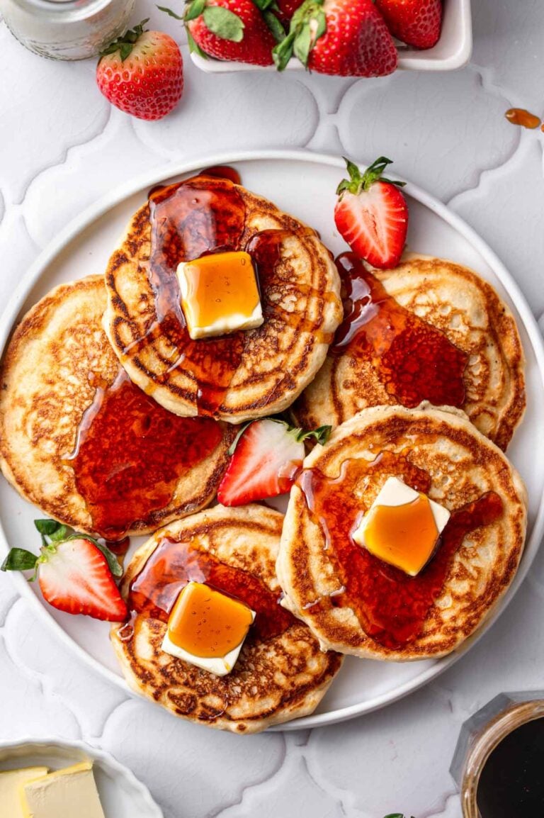 a platter with pan fried vegan pancakes made with dairy-free buttermilk topped syrup and butter pats.