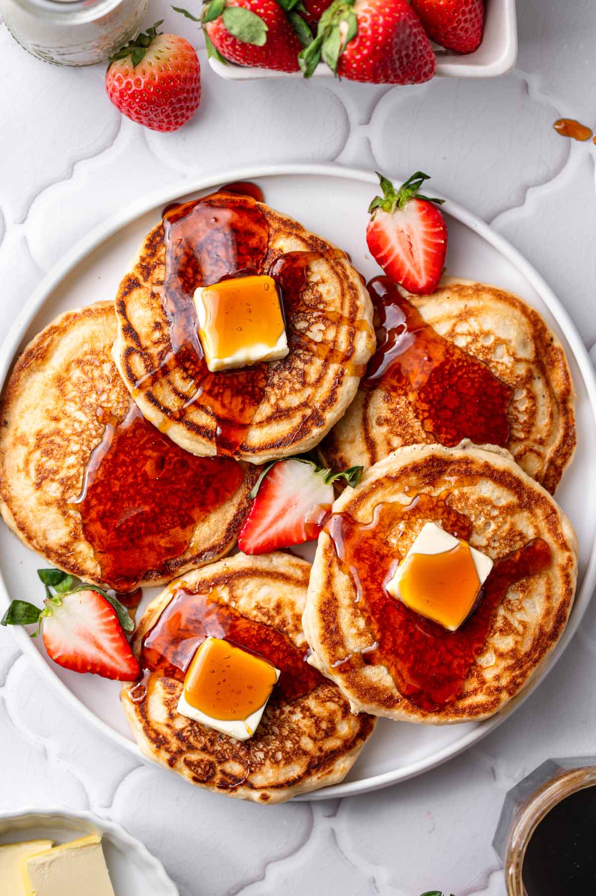 a platter with pan fried vegan pancakes made with dairy-free buttermilk topped syrup and butter pats.