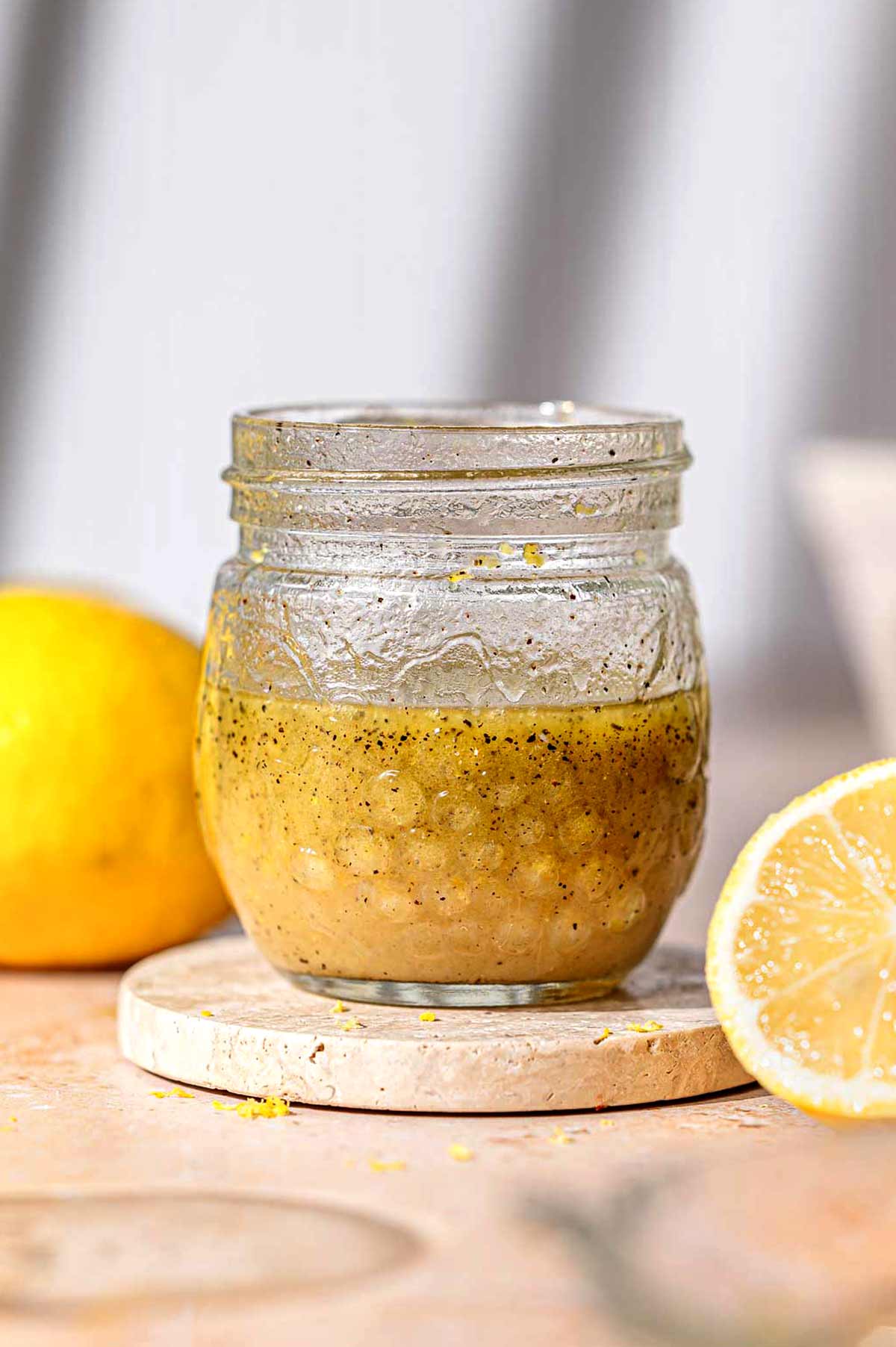 a small glass jar filled with homemade lemon dijon dressing.
