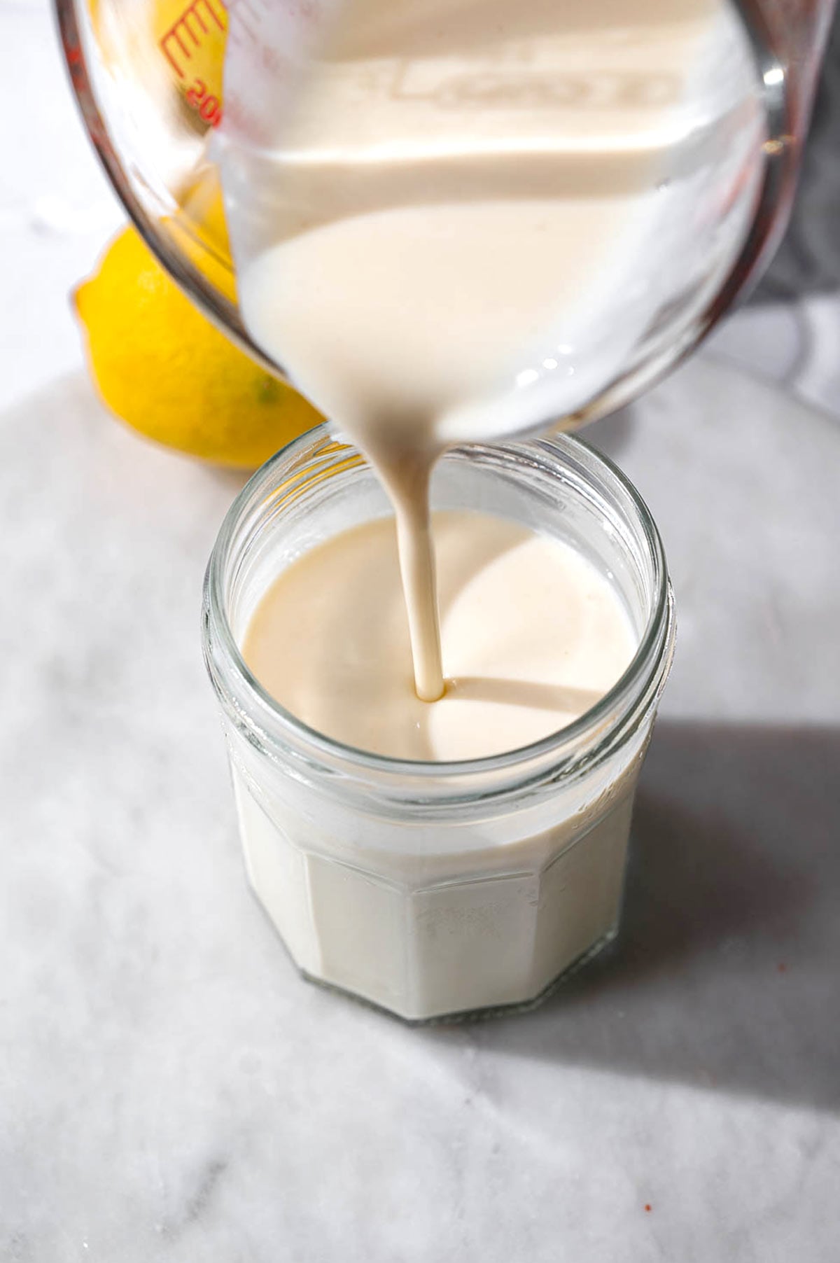 vegan buttermilk being poured into a glass jar.