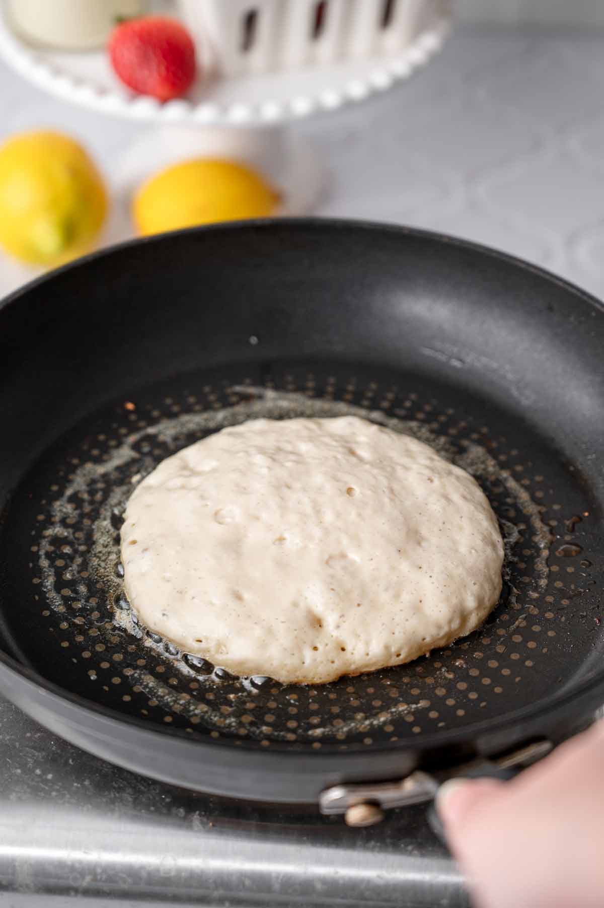 a vegan buttermilk pancake cooking in dairy-free butter in a nonstick pan.