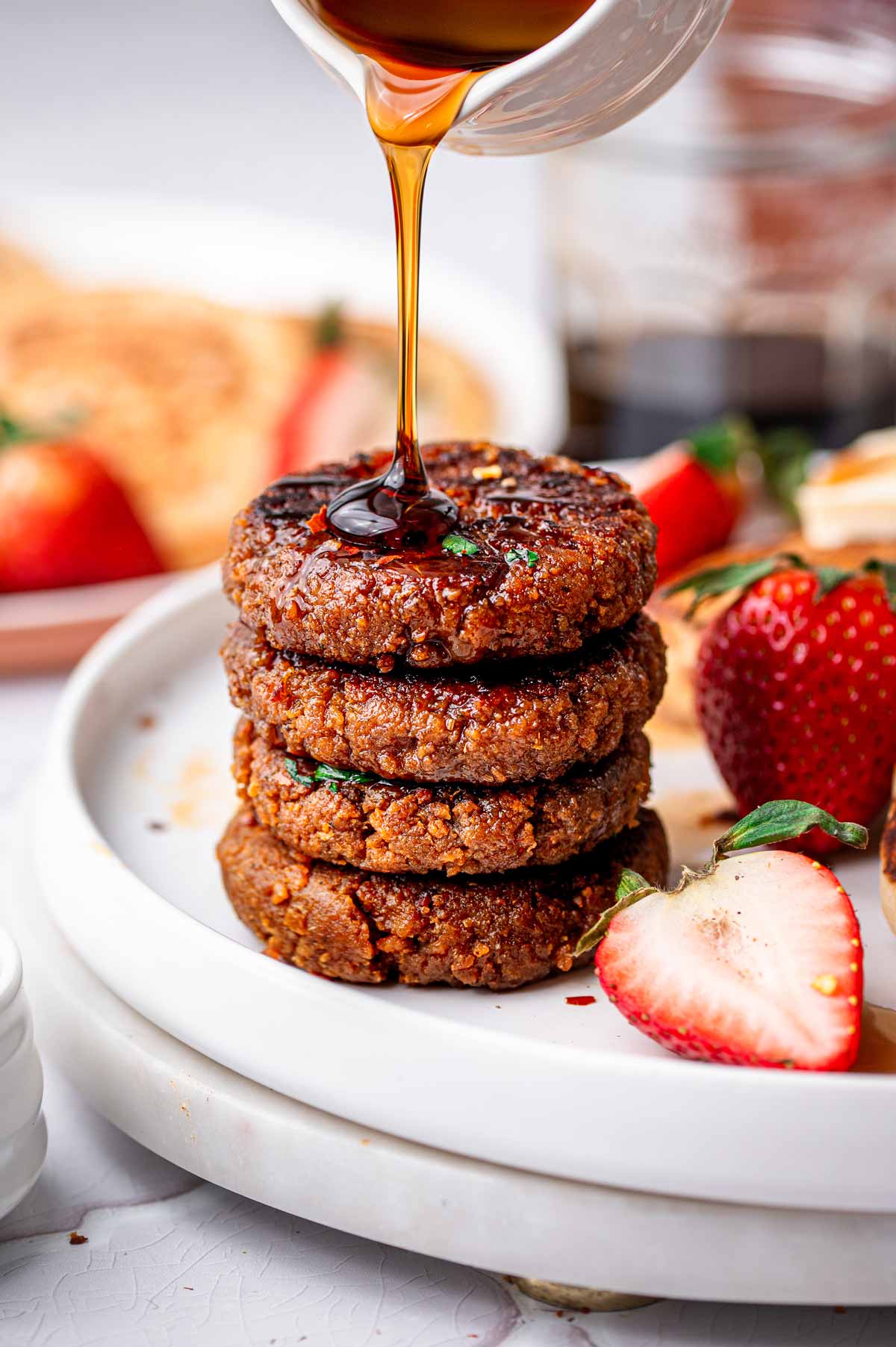 a stack of four vegan sausage patties with a drizzle of maple syrup on top.