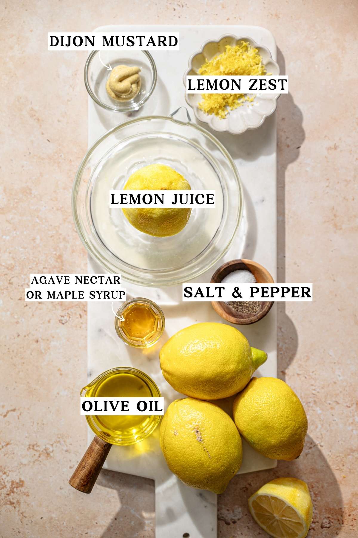 ingredients like lemons, olive oil, mustard and salt on a marble tray.