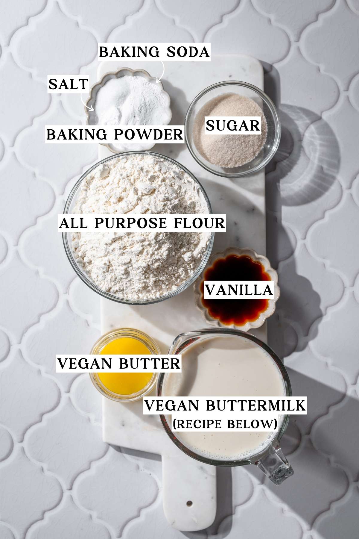ingredients like dairy free buttermilk, flour, baking powder and soda and vegan butter on a marble tray.