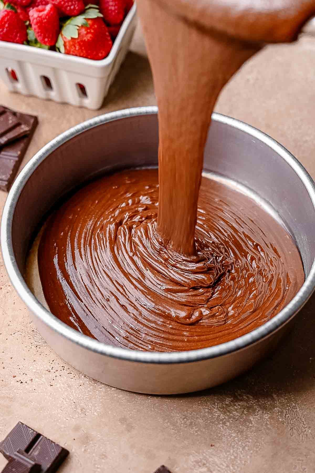 the vegan chocolate cake batter being poured into a pan.