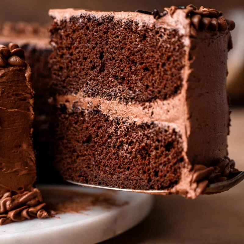 a slice of vegan chocolate cake on a spatula being lifted off a cake tray.