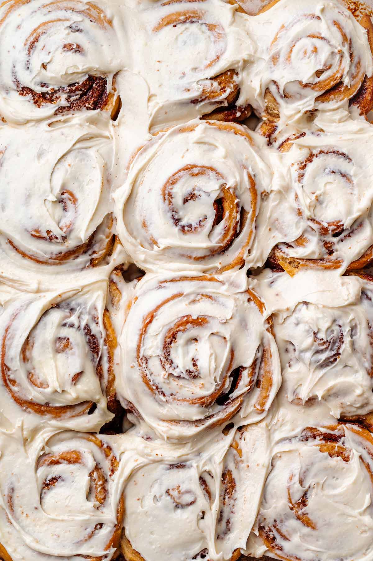 a tray of baked vegan cinnamon rolls with dairy-free cream cheese.