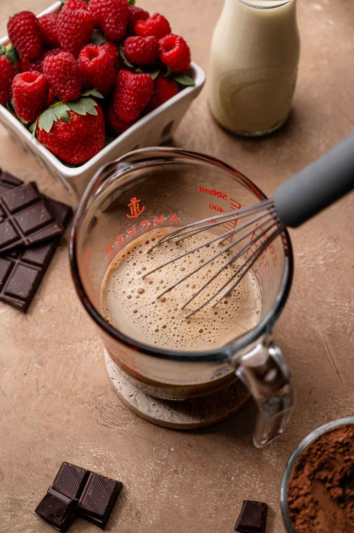hot soy milk and espresso powder mixed in a glass measuring cup.