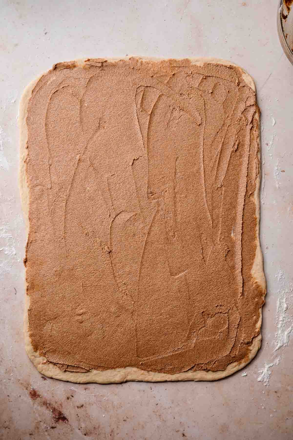 the rolled out eggless cinnamon roll dough with filling spread all the way to the edge.