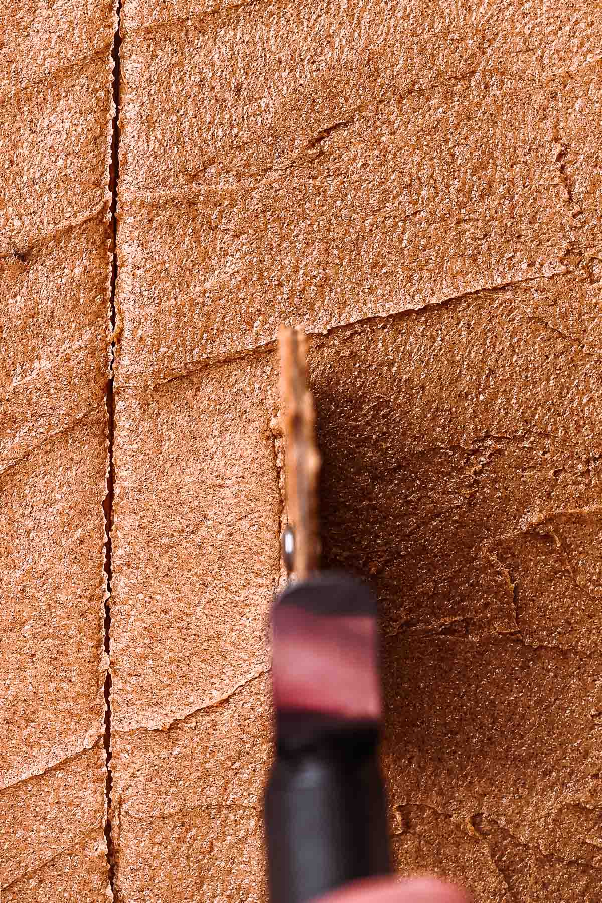 a hand cutting the cinnamon roll dough with a pizza wheel.