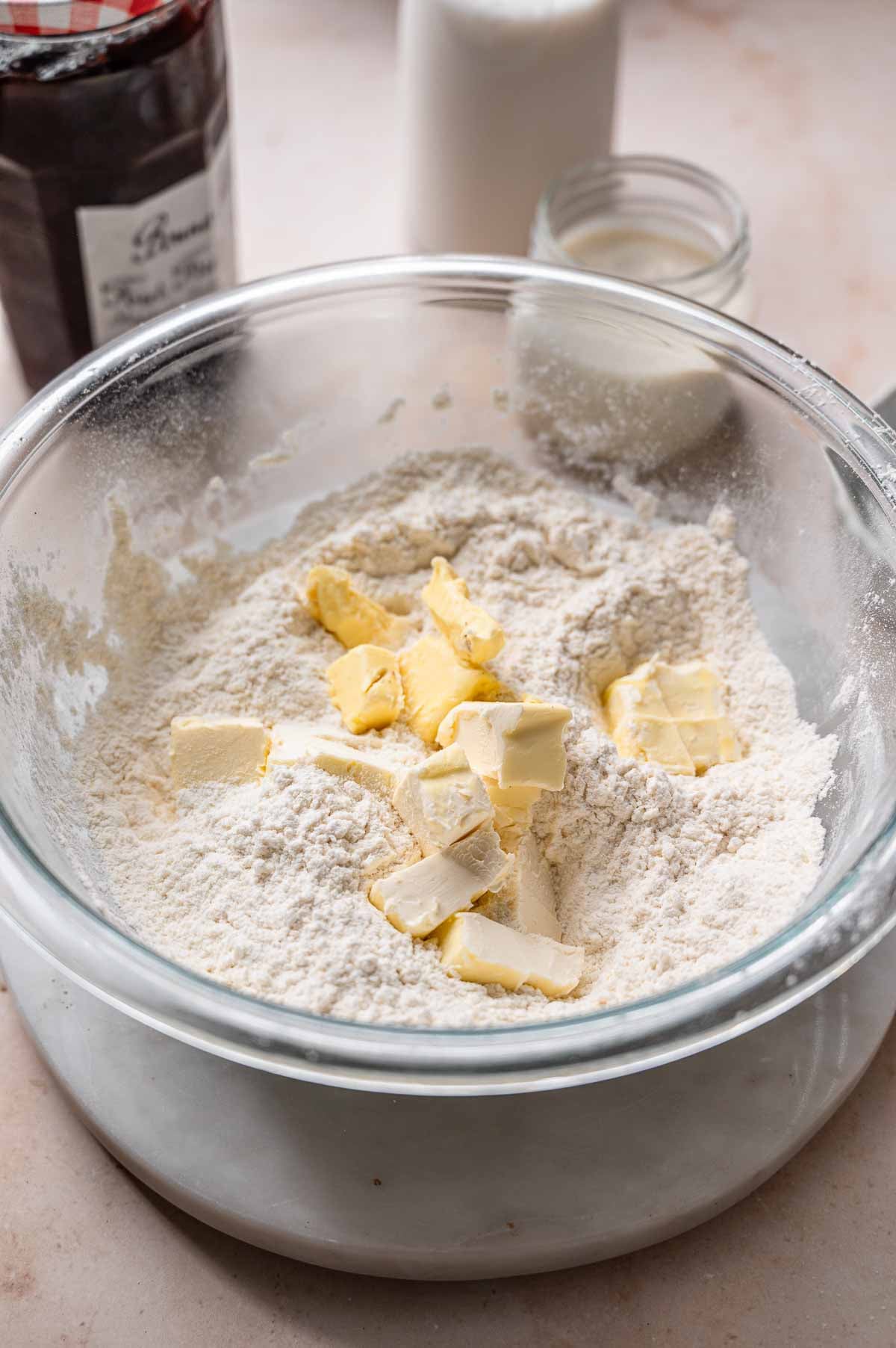 a large bowl with dry ingredients and cold dairy-free butter.