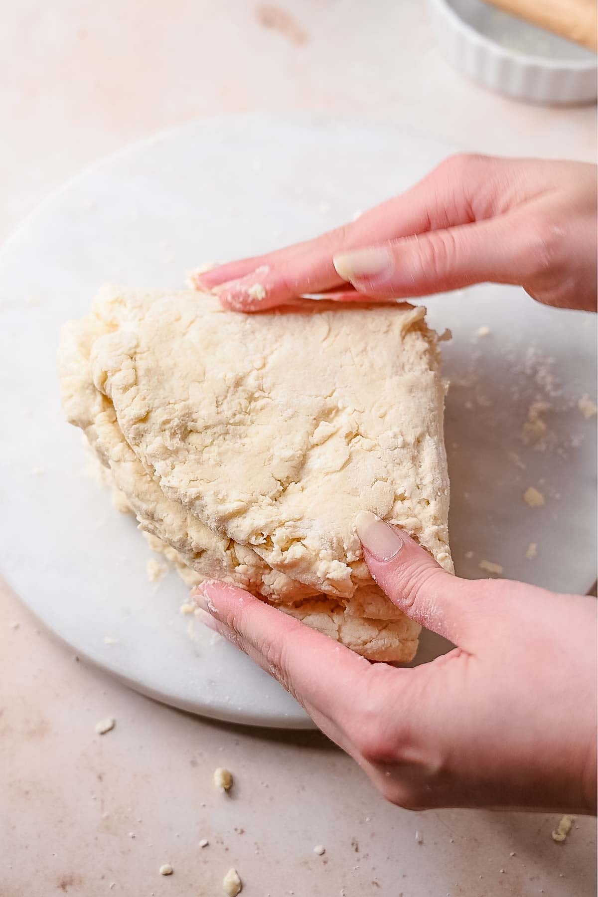 a hand folding the dough into quarters for tall flaky layers.